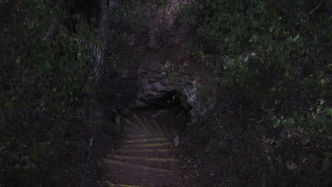 Ascending-shot-of-steps-leading-down-into-a-deep-dark-cave