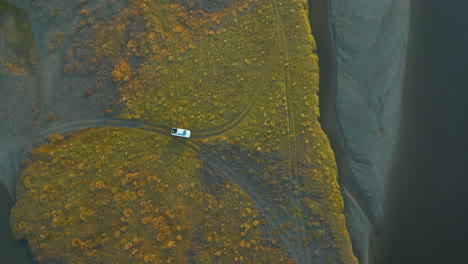 Stunning-birds-eye-view-of-a-truck-driving-on-a-dirt-road-near-the-grand-river-in-Argentina