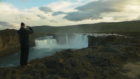 Person-on-holiday-in-Iceland-at-Godafoss-Waterfall-taking-pictures
