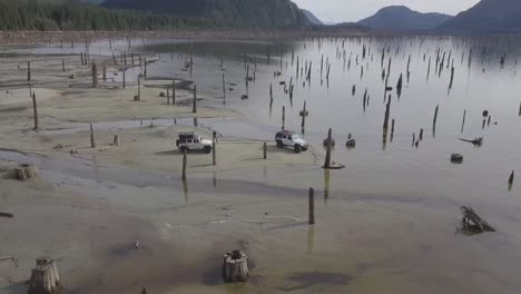 Drone-aerial-shot-of-two-jeeps-by-the-water-desert-in-No-Man's-Land-in-British-columbia