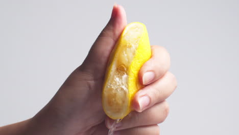 Hand-squeezes-lemon-juice-on-a-white-background,-isolated