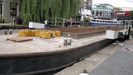 Narrowboat-with-container-for-construction-and-industry-transportation-being-pulled-out-of-lock-chamber-at-Regent's-canal