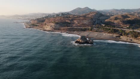 Cinematic-aerial-zoom-in-on-the-famous-Raven-Rock-of-El-Peñón-del-Cuervo-that-splits-the-bay-into-two-beaches-on-the-coast-of-the-Alboran-Sea-in-Malaga-Spain