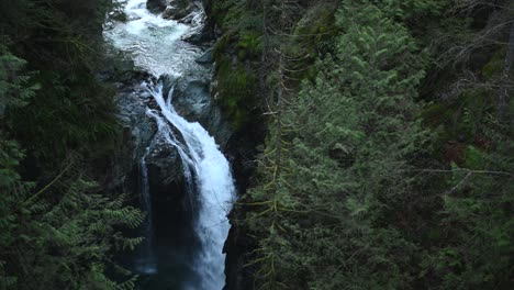 Filmszene-Eines-Wasserfalls-Innerhalb-Einer-Klippe-Im-Regenwald-Des-Lynn-Valley-In-North-Vancouver,-BC,-Kanada,-Schwenk-Nach-Links