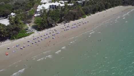 Beach-Umbrellas-On-The-Shore-Of-Four-Mile-Beach-In-Port-Douglas,-Australia---aerial-drone-shot