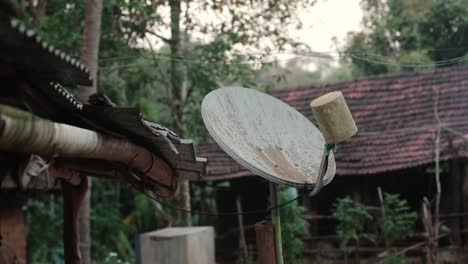 Outdoor-satellite-dish-on-top-of-wooden-house-roof-in-rural-area