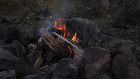 Campfire-shortly-after-being-lit-with-pine-logs-surrounded-by-boulders