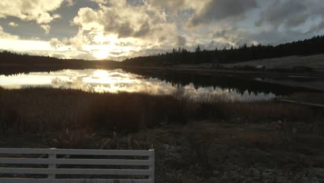Ruhiger-Blick-Auf-Den-See-Bei-Sonnenuntergang,-Ein-Bewölkter-Tag-Mit-Weiß-Gestrichenen-Ranchzäunen-In-British-Columbia,-Kanada