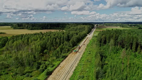 Vista-Aérea-De-Retorno-De-La-Maquinaria-De-Construcción-De-Carreteras-Que-Trabaja-En-El-Bosque-De-Letonia