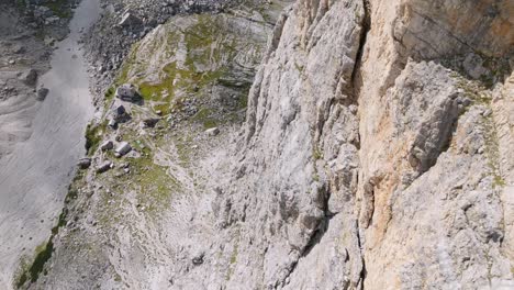 Ascend-top-down-shot-along-rocky-wall-of-mountain-in-sunlight---Brenta,-Dolomites