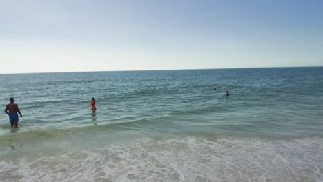 Several-people-walking-in-the-ocean-on-Anna-Maria-Island,-Florida