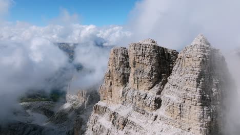 Hermoso-Vuelo-De-Drones-Sobre-La-Cumbre-De-Las-Montañas-Rocosas-Con-Nubes-Y-Niebla-En-El-Fondo---Montañas-Brenta-En-Italia