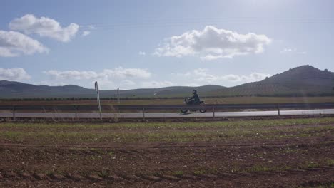 Motorcycle-Rider-Moving-on-Empty-Road-in-Rural-Countryside,-Parallel-Tracking-Shot