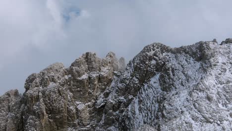 Aerial-push-out-shot-of-snowy-mountains-flying-through-clouds-in-Dolomites---Backwards-ascending-shot