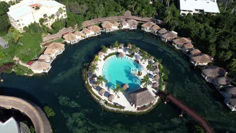 Aerial-View-of-Beautifull-Pool-Island-in-Lagoon-Surrounded-With-Bungalows-and-Rainforest,-Playa-Del-Carmen,-Mexico