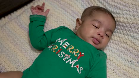 Entzückendes-Süßes-Indisches-Baby,-Das-Grünes-Festliches-Fröhliches-Weihnachtsoutfit-Trägt,-Das-Auf-Decke-Legt,-Während-Er-Sich-Umzieht