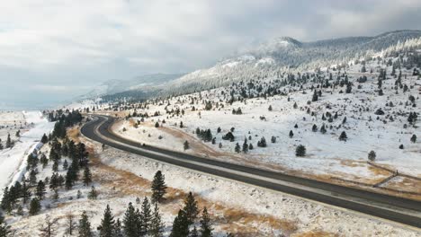 Coquihalla-Highway-5-between-Merritt-and-Kamloops-on-a-partly-cloudy-day-in-the-winter,-mountain-sides-covered-in-snow