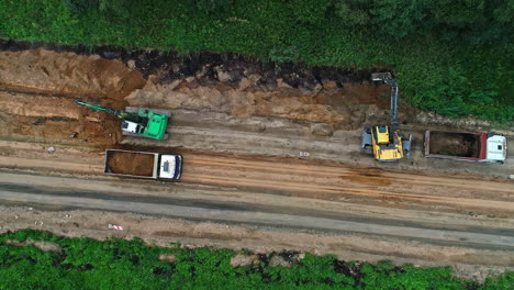 Aerial-top-down-view-over-road-construction-working-machinery-and-trucks