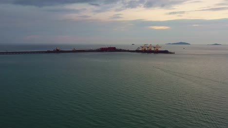 Aerial-drone-flyover-straits-of-malacca,-sea-in-west-coast-Malaysia-capturing-the-export-wharf-of-brazilian-vale-iron-ore-mining-corporation,-logistic-bulk-teluk-rubiah-terminal-at-dusk