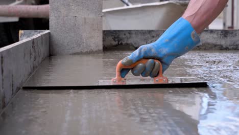 Person-with-blue-gloves-paving-the-cement-flat