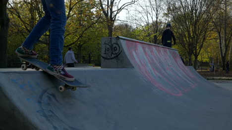 Cinematic-shot-of-kid-on-board-of-skateboard-drops-in-ramp-at-local-skatepark