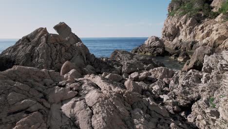 Close-up-rocks-and-stones-on-jagged-coastline-with-sea-in-background