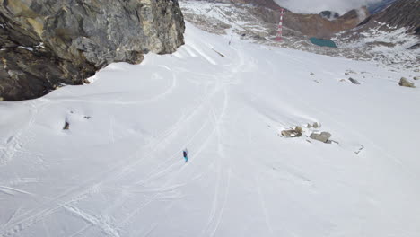 Aerial-top-down-shot-of-snowboarder-skiing-down-the-snowy-slope-of-hill