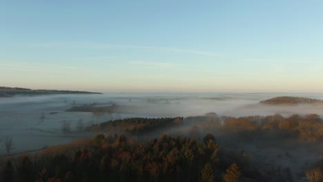 Drone-reveal-of-low-hanging-fog-and-mist-over-british-countryside-in-on-frosty-morning-at-sunrise