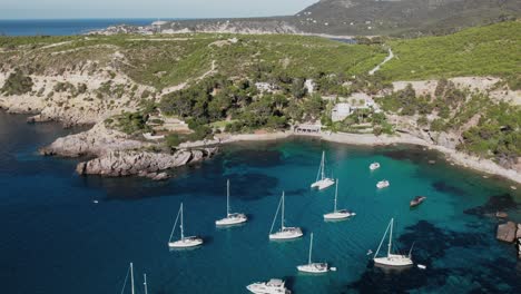 Drohnenaufnahme-Von-Yachten-Und-Segelbooten-Am-Strand-Von-Es-Canaret-In-Ibiza,-Spanien