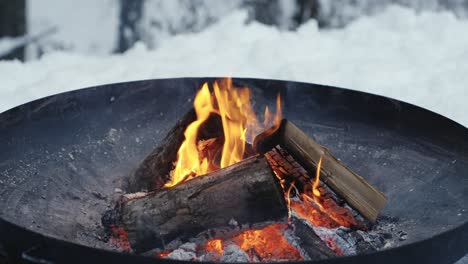 Closeup-of-outdoor-fire-pit-during-a-winter-snowy-day-in-backyard-terrace