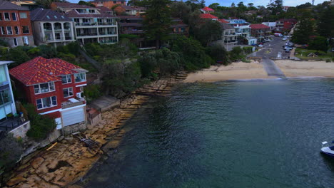 Drone-pan-along-houses-onto-foreshore-over-an-inlet-with-a-boat-and-ramp