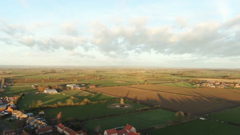 Leuchtender-Sonnenuntergang-über-Den-Großen-Flachen-Feldern-Von-Yorkshire-In-England,-Die-Von-Einem-Kleinen-Dorf-Umgeben-Werden