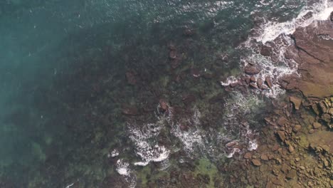 Luftaufnahme-Von-Oben-Nach-Unten-Von-Blauen-Meereswellen,-Die-über-Felsen-In-Der-Berühmten-Bucht-Von-Cadiz-Krachen