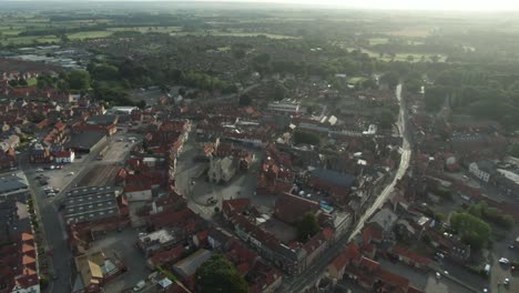 Drone-shot-puling-out-off-historic-English-market-town-centre-with-church-at-golden-hour-sunrise