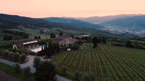 Aerial-View-Of-A-Tuscan-Villa-Surrounded-By-Vineyards-In-Italy-At-Sunset,-Sunrise