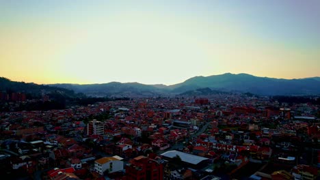 Evening-with-clear-yellow-sky-between-the-mountain-with-a-zenithal-flight-from-a-drone-view-over-the-red-roofs-of-the-houses-of-the-small-town