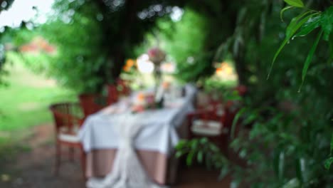 Pushing-Focus-to-Wedding-Table-Decorated-With-Flowers,-Candlesticks-For-Couple-and-Parents-In-a-Garden-Outdoors