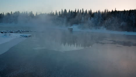 Creepy-frosty-morning-mist-rising-from-cold-alpine-woodland-frozen-lake,-Sweden