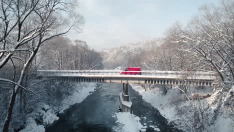 Aerial-shot-of-red-van-crossing-the-snowy-bridge-in-winter-morning