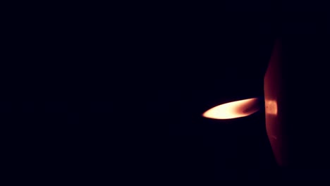 Vertical-rotation-of-single-big-yellow-candle-flame-lights-isolated-on-a-black-background