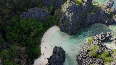 Revealing-aerial-shot-of-isolated-beach-with-white-sand-hidden-by-steep-cliffs