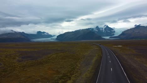 Drone-following-a-car-going-on-Iceland-road-towards-the-snowcapped-mountains