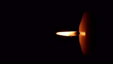 Vertical-rotation-of-single-big-yellow-candle-flame-lights-isolated-on-a-black-background