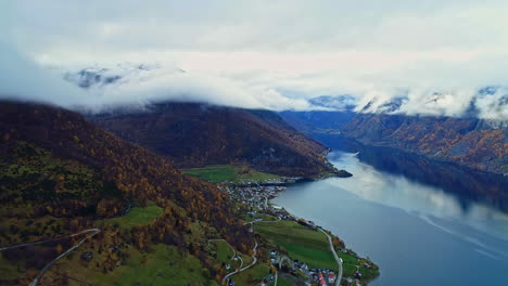 Pueblo-Frente-Al-Mar-En-El-Fiordo-Verde-Noruego-En-Noruega-Con-Montañas-Envueltas-En-Nubes