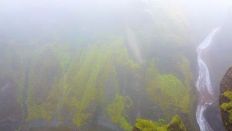 Aufnahme-Durch-Den-Nebel-über-Den-Fließenden-Fluss-In-Der-Schlucht-Und-Einen-Wasserfall,-Der-Dorthin-Führt