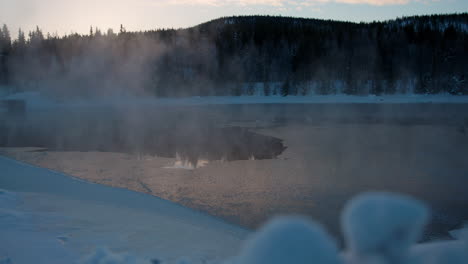 Dreamy-frosty-morning-mist-rising-from-cold-alpine-woodland-frozen-lake-at-sunrise,-Sweden