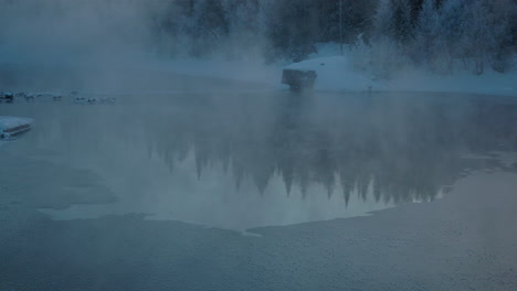 Frosty-morning-mist-rising-from-cold-alpine-woodland-frozen-lake,-Norbotten