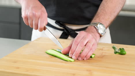 male-chef-slicing-the-green-cucumber-with-the-tip-of-the-sharp-knife