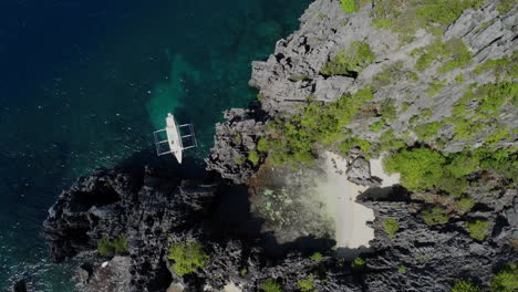 Top-aerial-view-of-boat-anchored-at-hidden-beach-on-rocky-coastline