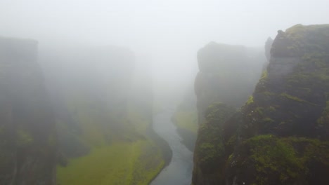 Drone-flying-in-the-mist-on-Icelandic-river-rocky-mountainous-terrain-with-poor-visibility-and-sense-of-mystery-rugged-canyon-walls